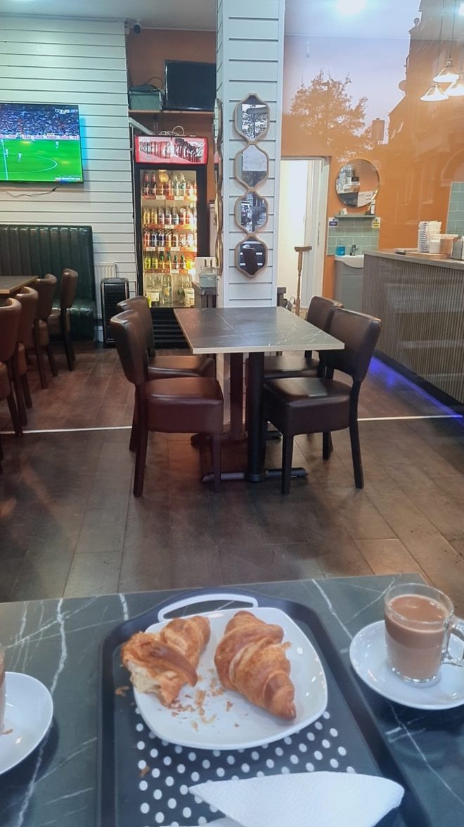The room seen past a tray of coffee and a croissant